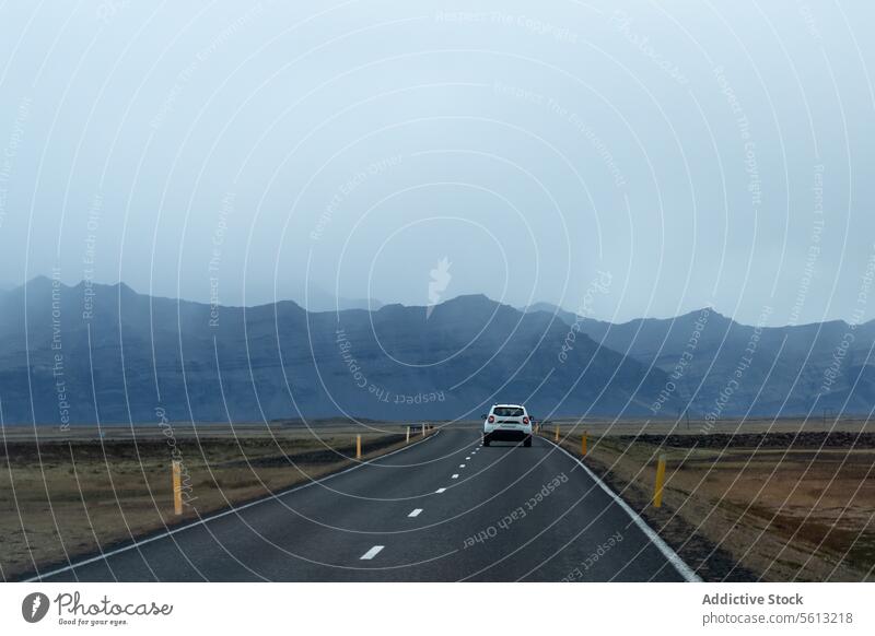 Back view of a car traveling on road through the misty highlands of Iceland under cloudy sky iceland adventure solitude thorsmork valley landscape scenery