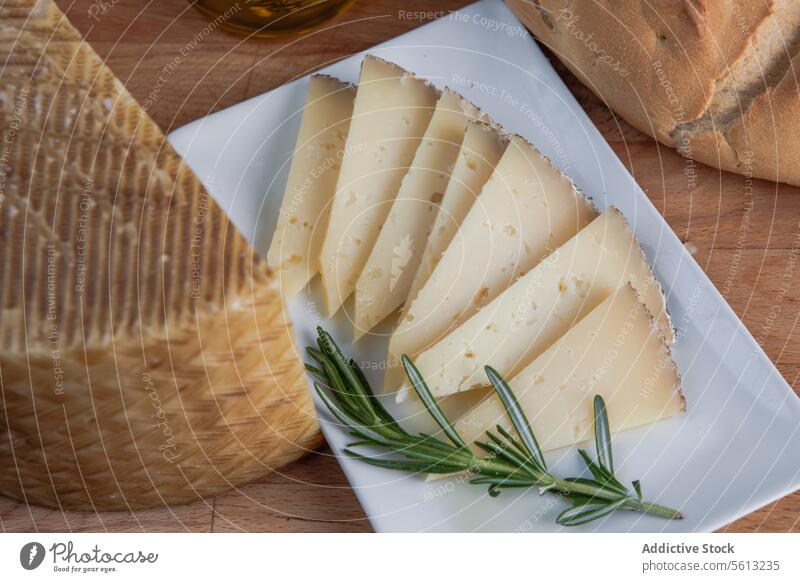 Artisan cheese slices with fresh herbs and bread artisan rosemary plate olive oil food dairy gourmet wooden table cuisine culinary snack appetizer breakfast