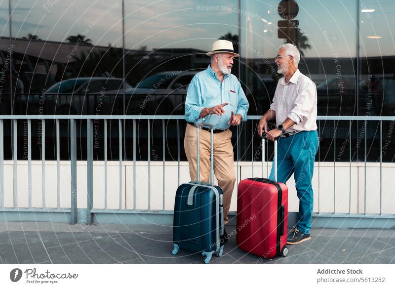 Aged male travelers waiting outside airport friends senior men suitcase footpath railing valencia full body luggage stand vacation together retired lifestyle