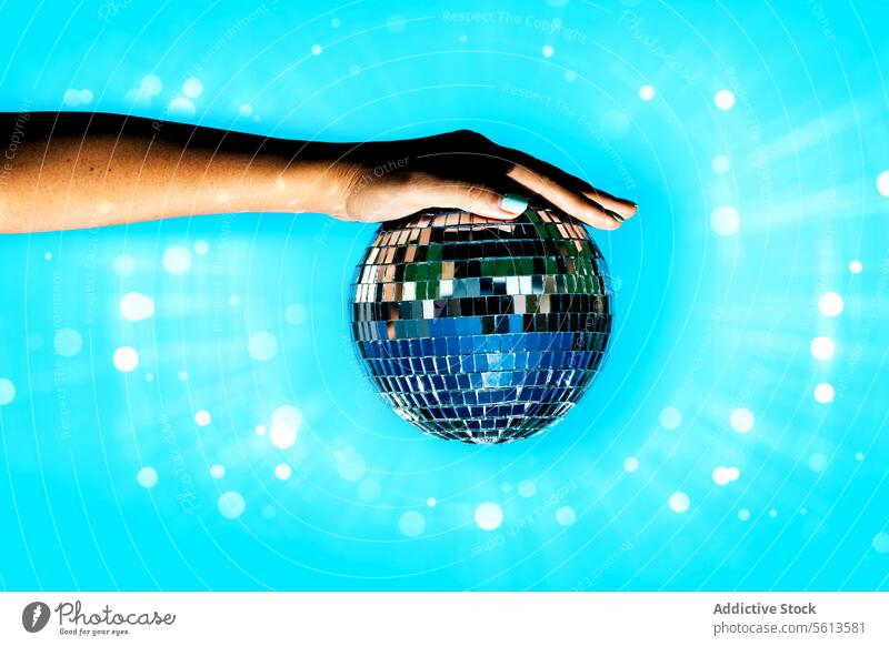 Woman holding disco ball against illuminated background hand woman bright party lens flare anonymous trend club shiny blue trendy faceless isolated nightclub
