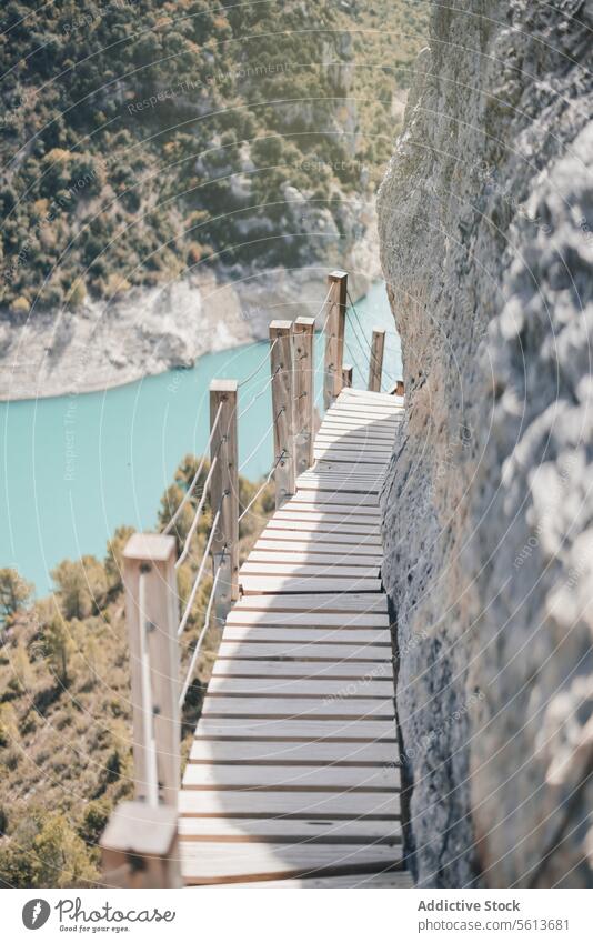 Wooden footpath on rocky mountain empty wooden narrow pathway formation downhill river sunny railing cliff travel nature water environment geology high bridge