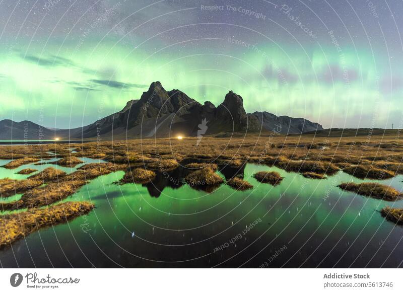 Stunning aurora borealis over mountainous landscape at night in Eystrahorn, Iceland sky reflection water rugged peak starry view breathtaking northern lights