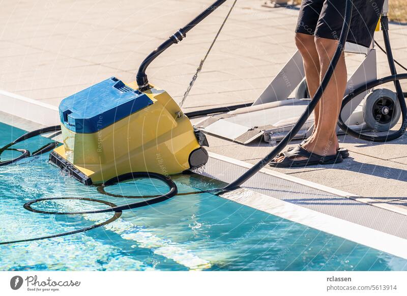 Pool cleaning robot being placed by a person next to a swimming pool woman service industry technician uniform robotic cleaner pool care summer pool equipment