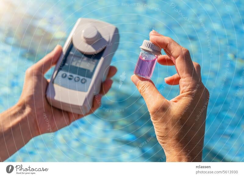 person testing swimming pool water with a digital test device and a small sample container ph testing chemical balance ph strips poolside hand ph level filter