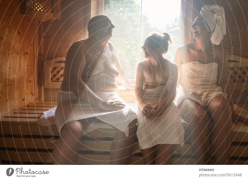 family in a finnish sauna, man on the left, woman with towel on head on the right, child in center at spa hotel finland spa wellness relaxation wooden bench