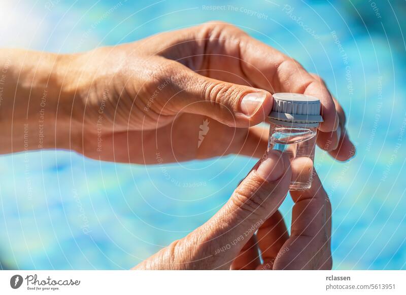 Close-up Hands closing a vial of water for pH testing near a swimming pool at a hotel ink liquid yellow liquid value chlorine measure sample hygiene summer