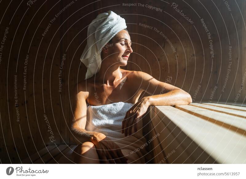 Elderly woman sitting relaxed in a wooden sauna attractive bath bathrobe beautiful beauty beauty spa body calm care caucasian comfortable enjoy female finland
