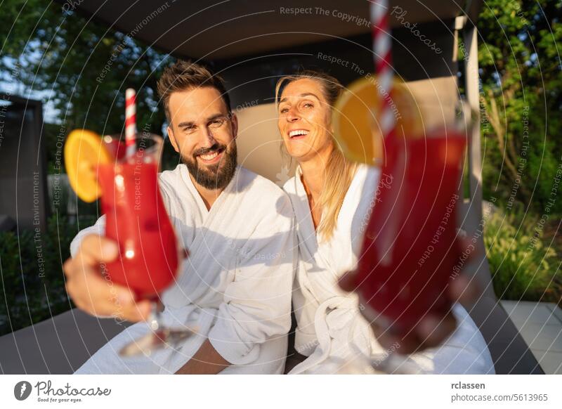 joyful couple in white spa robes enjoying red cocktails at a wellness resort bathrobe hotel spa wellness resort white robes relaxation leisure luxury vacation