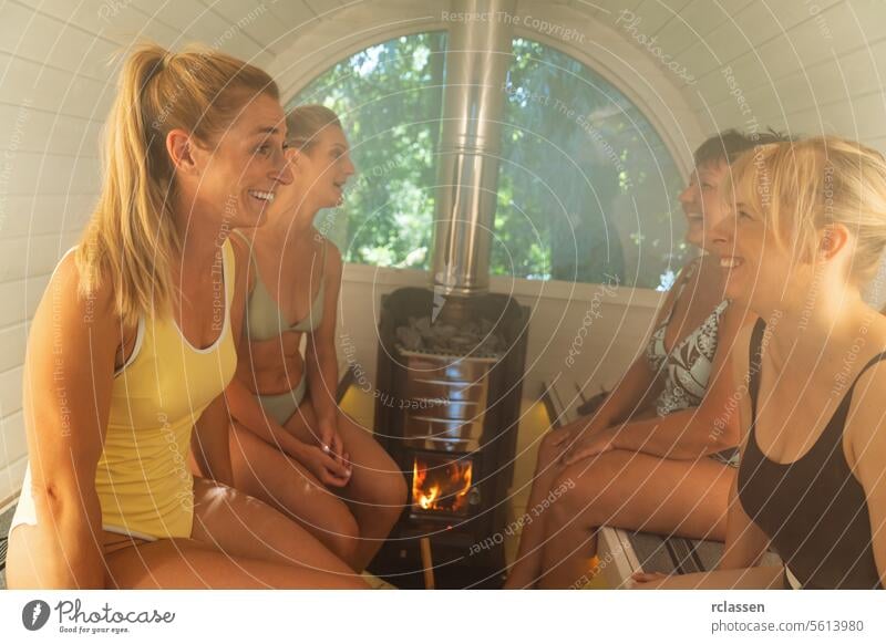 Four women enjoying a conversation in a brightly lit Finnish barrel sauna with a stove. finnish barrel sauna sauna stove enjoyment wellness health relaxation