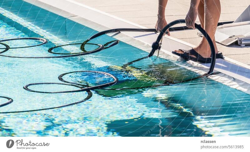 Person using a hose from a pool cleaning robot on the edge of a swimming pool woman service industry technician uniform robotic cleaner pool care summer