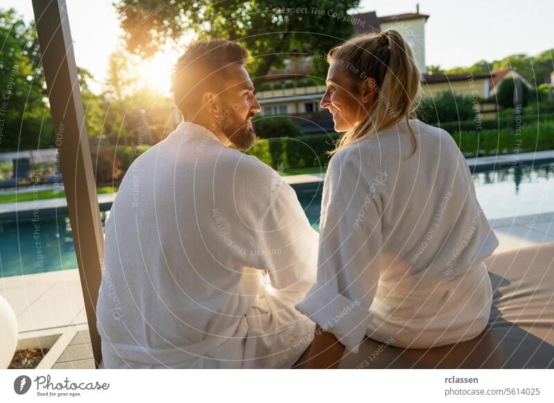 Couple in love looking to each other white bathrobes enjoying sunset by a pool in a spa wellness hotel resort white robes couple relaxation leisure enjoyment
