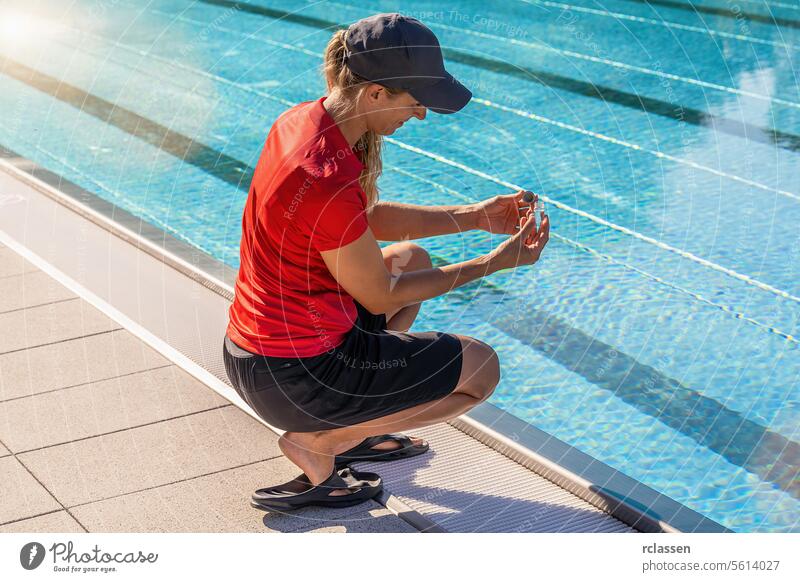Technician squatting by a pool while examining a water sample in a small vial for pH testing ink liquid yellow liquid value chlorine measure hygiene summer
