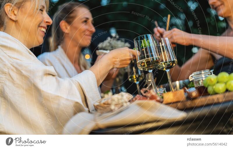 Friends enjoy wine and food outdoors near a Finnish mobile sauna at dusk friends finnish sauna gathering relaxation togetherness enjoyment wine glasses meal