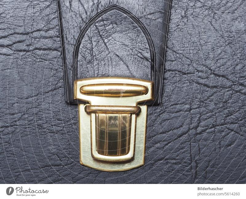 Kofferverschluss an einer schwarzen Aktentasche ledertasche lederkoffer verschluß metallverschluß aktentasche arbeitstasche bürotasche detail lederstruktur