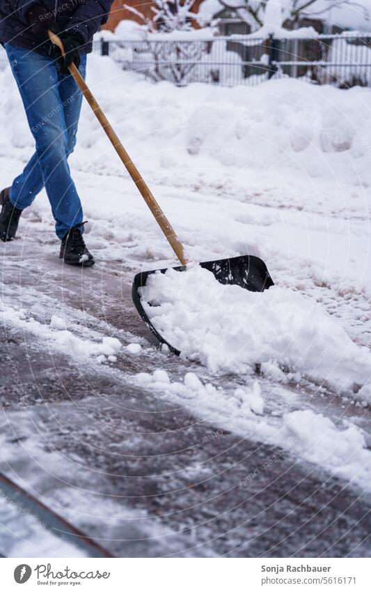 A man clears snow from a street with a snow shovel Man Snow shovel Winter maintenance program Traffic infrastructure Street Weather Snowfall Smoothness