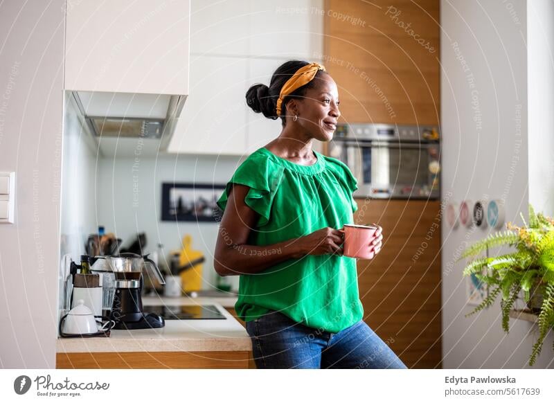 Portrait of a smiling mature woman standing in her kitchen drinking coffee people joy black natural attractive black woman happiness happy real people adult