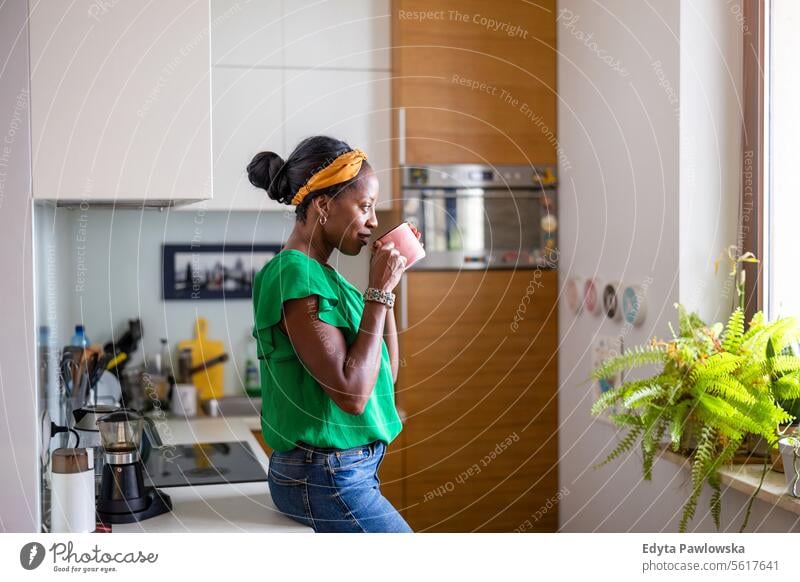 Portrait of a smiling mature woman standing in her kitchen drinking coffee people joy black natural attractive black woman happiness happy real people adult