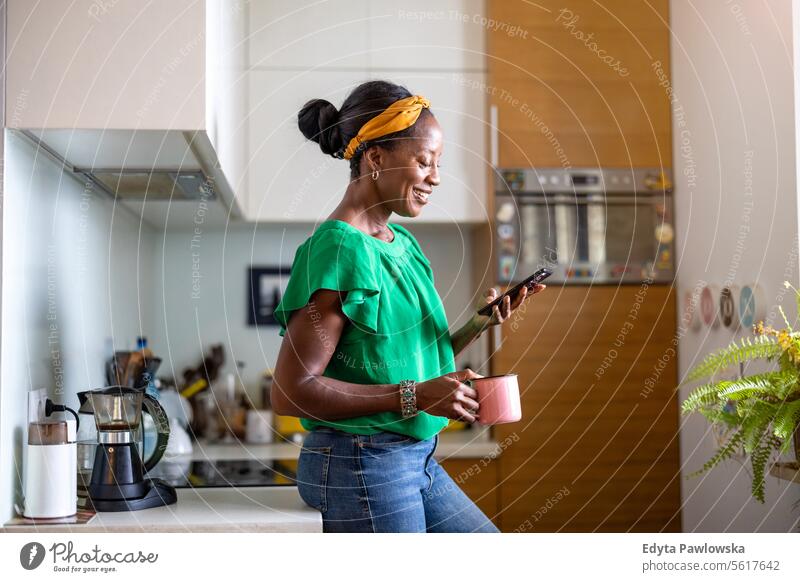 Mature woman using smartphone in the kitchen at home people joy black natural attractive black woman happiness happy real people mature adult daily life adults