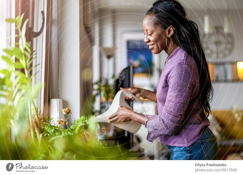 Beautiful woman watering plants at home people joy black natural attractive black woman happiness happy real people mature adult daily life adults one person