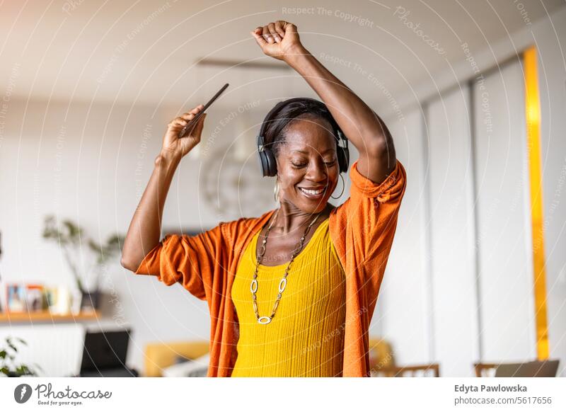Woman listening to music with headphones in the living room at home people joy woman black natural attractive black woman happiness happy real people mature