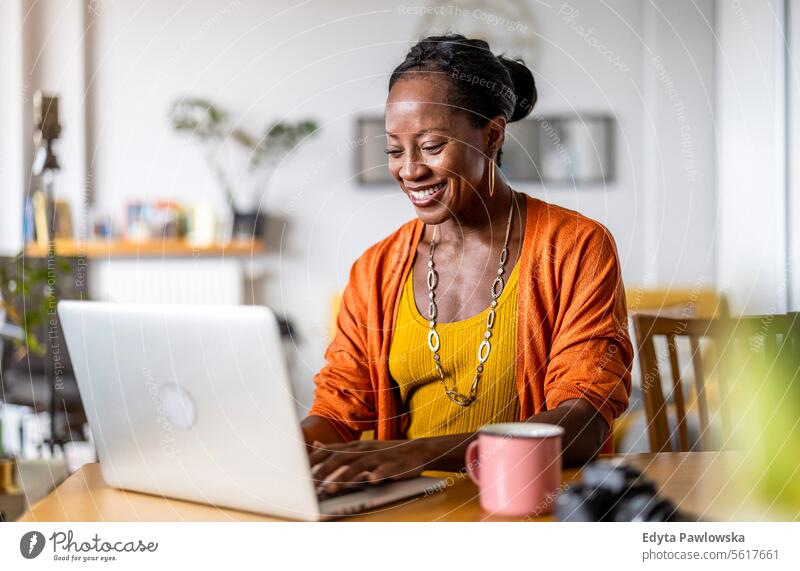Smiling woman working on her laptop at home people Joy Woman Black naturally Attractive black woman Happiness Happy real people Mature more adults daily life