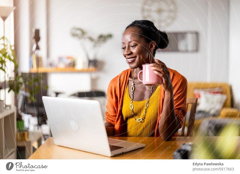 Smiling woman working on her laptop at home people Joy Woman Black naturally Attractive black woman Happiness Happy real people Mature more adult Everyday life