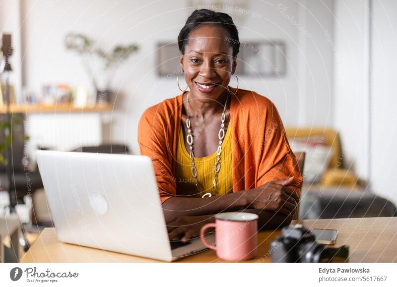 Smiling woman working on laptop at home people joy black natural attractive black woman happiness happy real people mature adult daily life adults one person