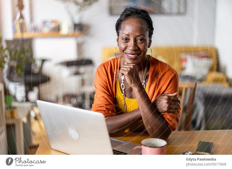 Smiling woman working on laptop at home people joy black natural attractive black woman happiness happy real people mature adult daily life adults one person