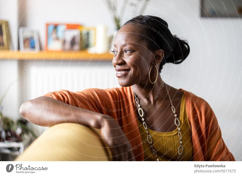 Portrait of smiling woman relaxing on sofa at home people joy black natural attractive black woman happiness happy real people mature adult daily life adults