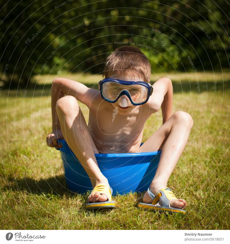 Boy wearing swimming mask sitting in a washbowl with water on a hot summer day 7 years activity boy caucasian child childhood close-up daylight equipment