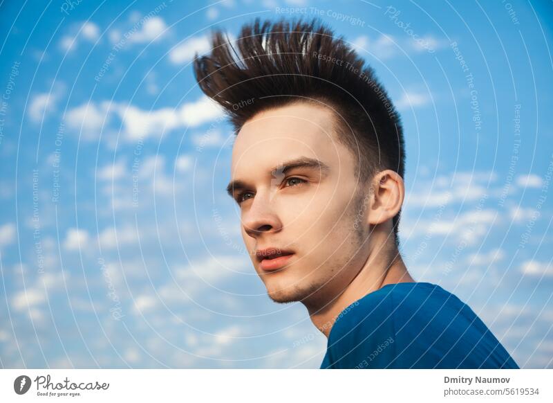 Outdoor portrait of teenager boy looking away with hair blowing in the wind against evening sky Generation Z alone attractive calm candid casual caucasian