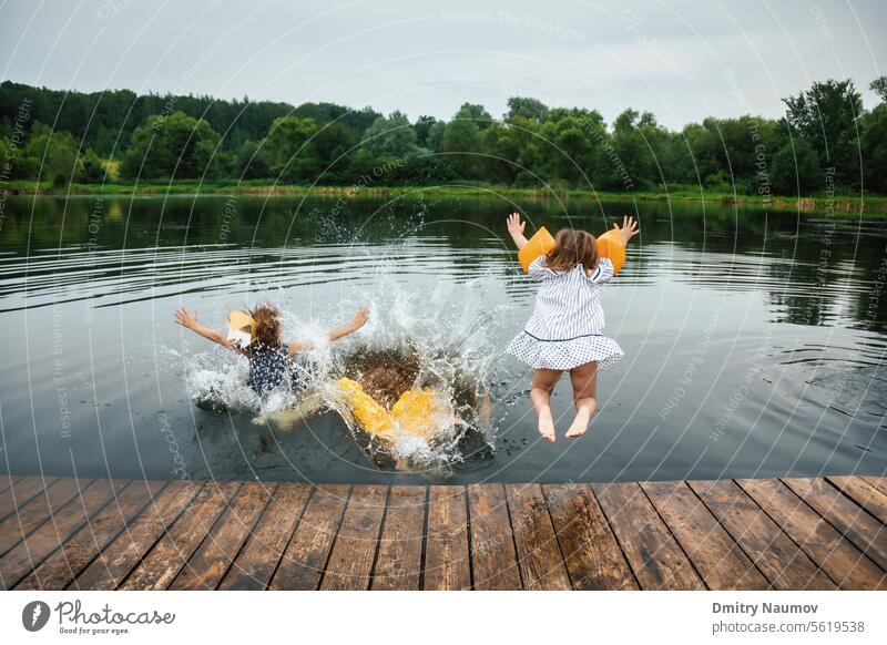 Children having fun on a lake jumping into water activity carefree child childhood children deck dress enjoy enjoyment freedom friends friendship girls group