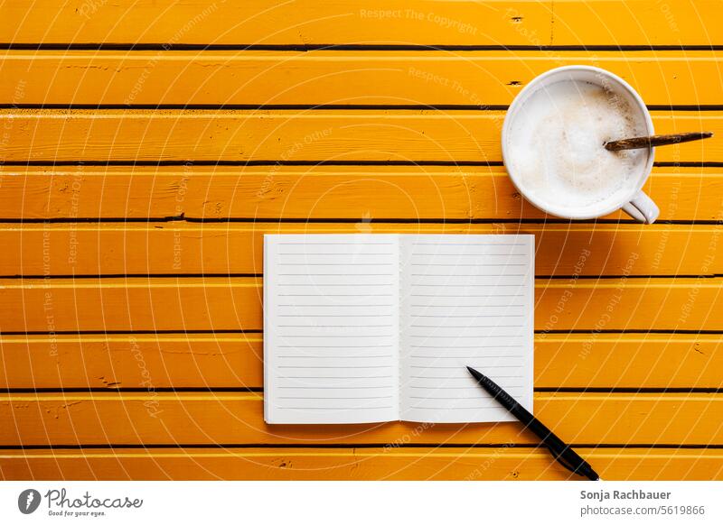 A cup of coffee and a notebook on a yellow wooden table. Top view Coffee Cup Notebook Ballpoint pen plan Table Wood Yellow Beverage Breakfast Hot Morning