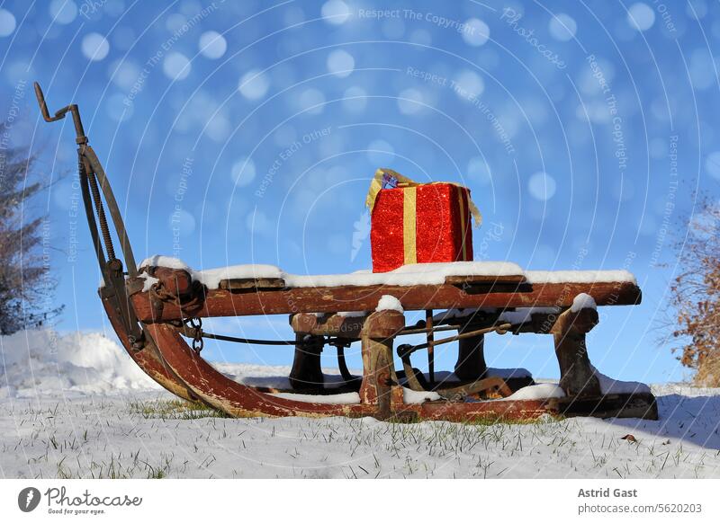 A large red gift package on a wooden sleigh with snow crystals in the sky Gift Sleigh Christmas Winter Snow Package gifts Donate Advent christmas holidays