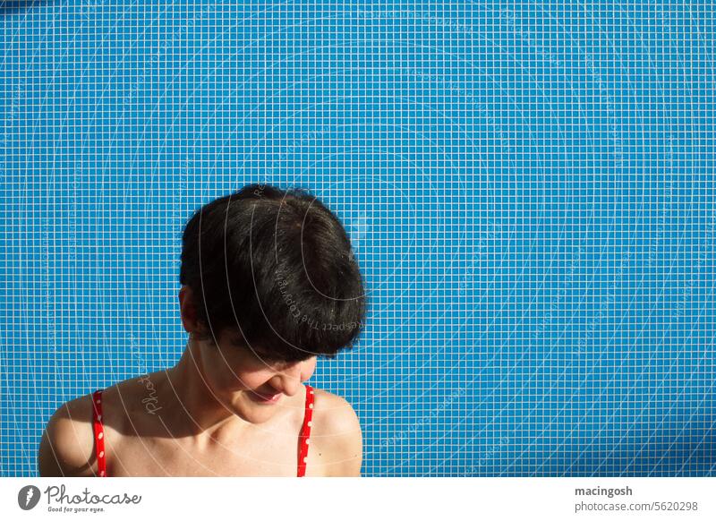 Young woman with black hair in front of blue tiled wall in swimming pool Swimming pool Interior shot Sunlight Summer vacation Relaxation holidays be afloat