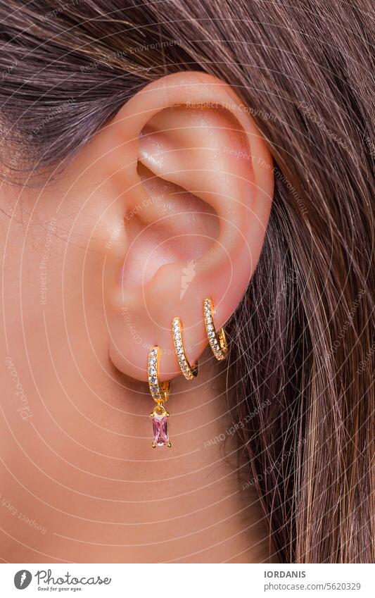Woman ear with mulriple piercings wearing beautiful earrings with zirconia accessories accessory attractive beauty close-up closeup design detail elegance