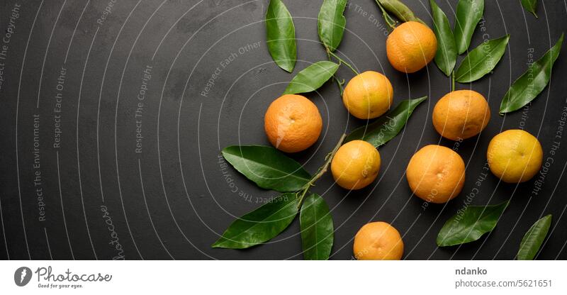 A ripe clementine with green leaves on a black table, top view orange leaf fruit citrus healthy organic nutrition nobody freshness sweet tasty vitamin juicy