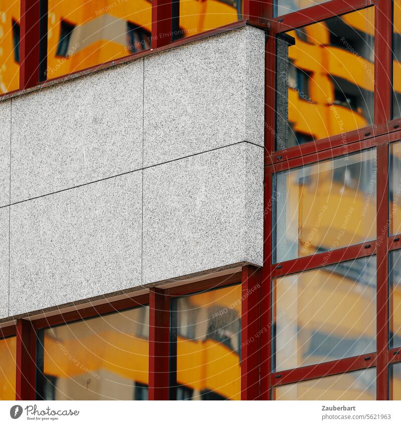 The yellow façade of a high-rise building is reflected in a glass façade with red frames, in between concrete elements, urban living Facade High-rise Yellow