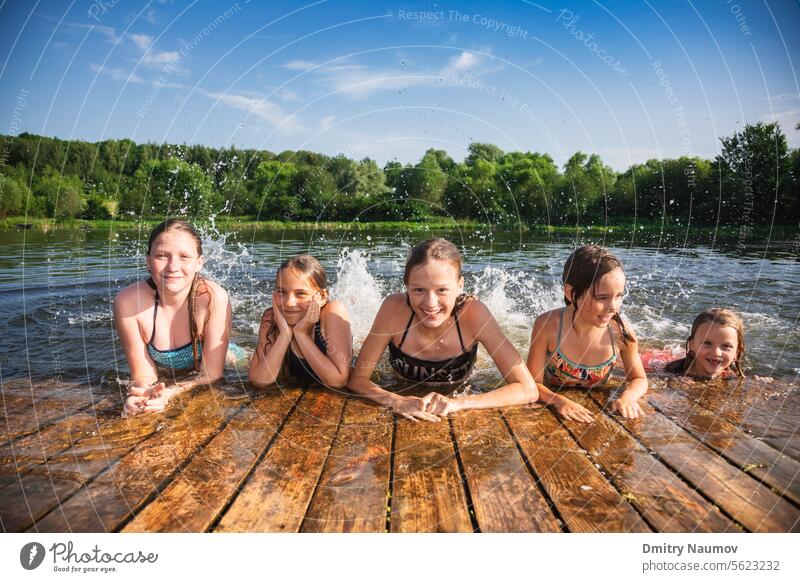 Happy little girls having fun playing in a lake splashing water during summer holidays activity carefree child childhood children deck emotion enjoy enjoyment