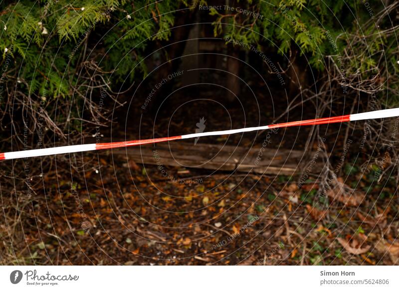Barrier tape in front of dark hiding place barrier tape cordon Hiding place Cave Entrance Safety Creepy darkness Crime scene forbidden Passage peril