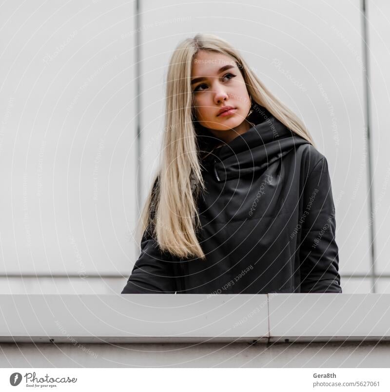 young girl with blond hair and black clothes against a gray building adult architecture autumn beautiful beauty blonde city dreamy erase face fashion female