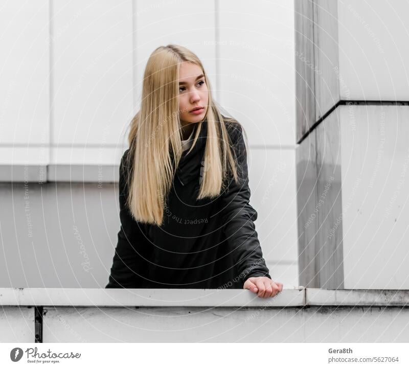 young girl with blond hair and black clothes against a gray building adult architecture autumn beautiful beauty blonde city dreamy erase face fashion female
