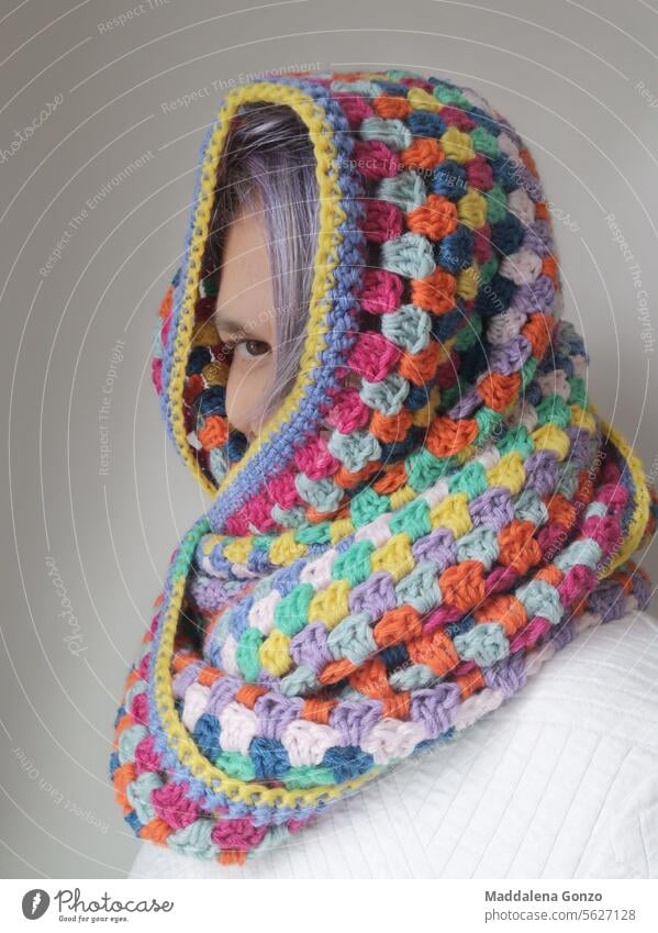 Person peaking out of multicoloured crocheted scarf handmade cozy warm warmth peek-a-boo colorful portrait peek a boo purple hair coloured hair oversize