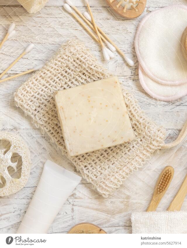 Beige handmade soap bar on soap saver bag near hygiene Items top view Soap Cleansing beige Hygiene skin care loofah sponge bamboo toothbrushes cotton swabs