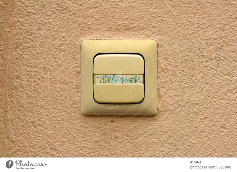 Push-button switch with the inscription DOOR OPENER on a beige-colored wall Switch Door opener Touch switch Pressure switch electrical installation