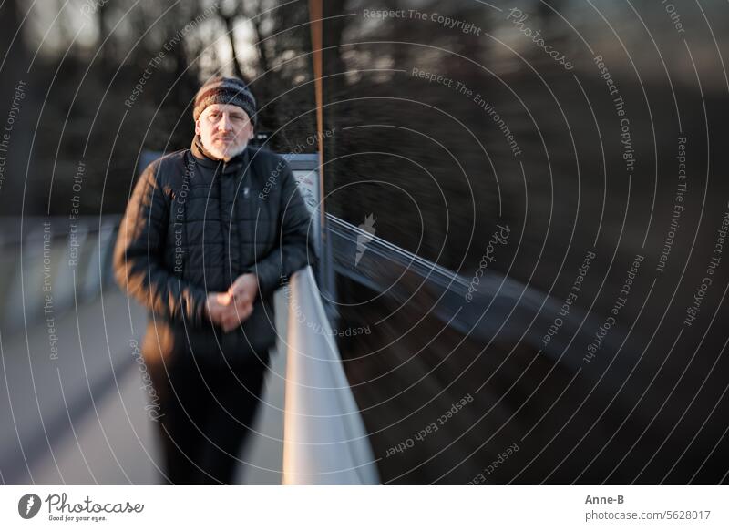 A man stands on the railing of a pedestrian bridge in the evening, surrounded by a lot of mystical blurriness. Man Winter Cold Twilight Stairs Bridge