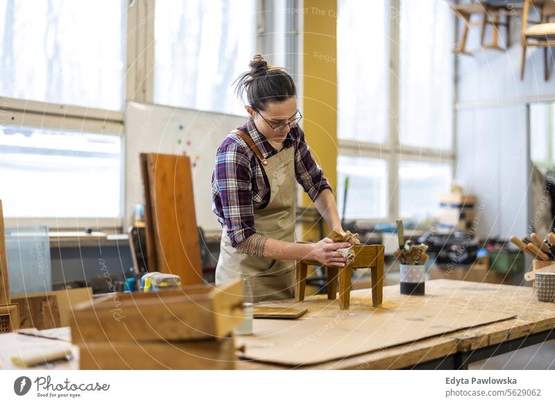 Portrait of young female carpenter working in her workshop Furniture Carpenter Restoring Carpentry wood Chair building Manufacturing Craft Renovation Repairing