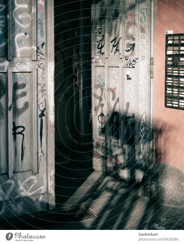 Open front door of a Gründerzeit apartment building, doorbell signs, graffiti and shadows a Entrance Front door founder time Graffiti Tags Shadow Bell