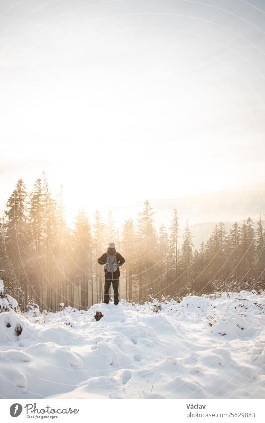 Traveller looks around the snowy landscape. Winter walk through untouched landscape in Beskydy mountains, Czech Republic. Hiking lifestyle. Sunrise at winter