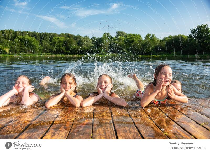 Happy little girls having fun playing in a lake splashing water during summer holidays activity carefree child childhood children deck emotion enjoy enjoyment